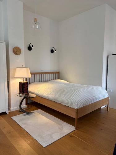 a bed in a room with a lamp on a table at Im Bademantel an den Strand - mit Terrasse in Eckernförde