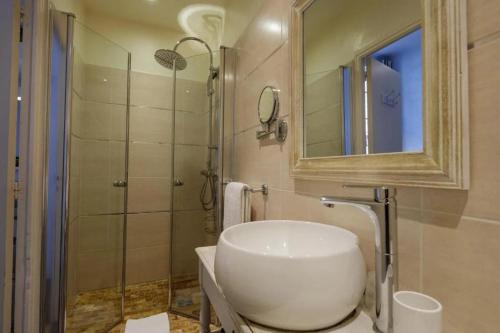 a bathroom with a sink and a shower with a mirror at Hôtel l'Amphithéâtre in Nîmes