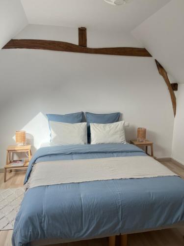 a bed with blue and white sheets and pillows at Le Petit Lavoir - Maison Cosy à Mayet in Mayet