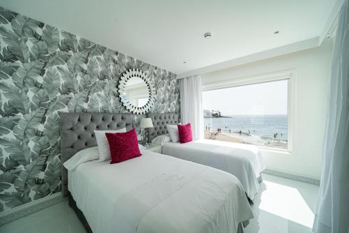 a bedroom with two beds and a window with the beach at Lani's Suites de Luxe - Adults Only in Puerto del Carmen