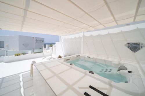 a bathroom with a bath tub in a white room at Lani's Suites de Luxe - Adults Only in Puerto del Carmen