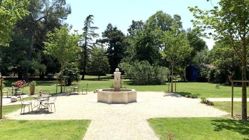 a fountain in a park with a table and chairs at Domaine de Rhodes - 5 Chambres et 7 locations de vacances in Avignon