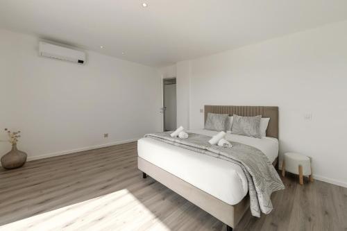 a white bedroom with a bed with two towels on it at Quinta Atia in Caldas da Rainha