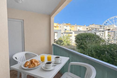 a table with croissants and cups of coffee on a balcony at Studio cosy clim - Piscine - Plage à pied - Cap d'Agde in Cap d'Agde