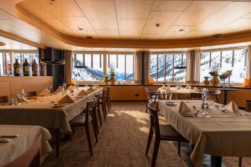a dining room with tables and chairs and windows at Wohlfühlhotel Hubertushof am Arlberg - Ski-In & Ski-Out - Sky Pool in Stuben am Arlberg
