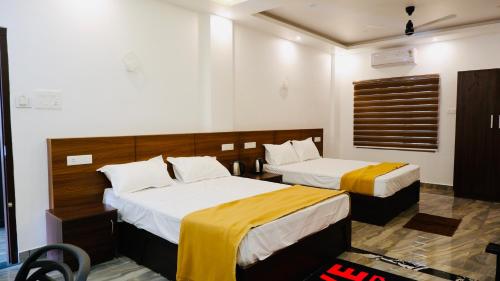 a hotel room with two beds with yellow and white sheets at Eettickal Homes in Ūdumbanshola