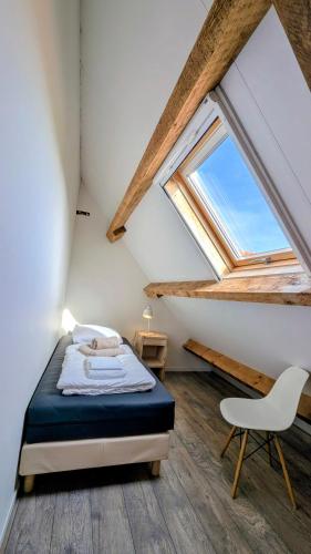a bedroom with a bed and a chair in a attic at Ballumerhoeve Tree Lodge in Ballum