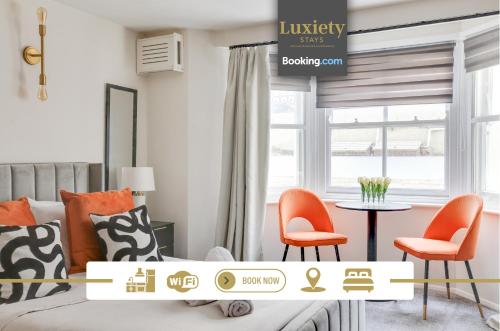 a bedroom with orange chairs and a bed and a table at Stylish Sunny Studio City Centre By Luxiety… in Southend-on-Sea