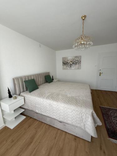 a white bedroom with a large bed and a chandelier at Urlaub am Bodensee in Staad - einmalige Seesicht in Staad