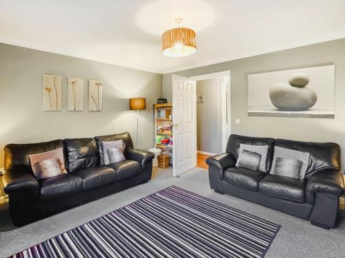 a living room with two leather couches and a rug at Brada View in Bamburgh