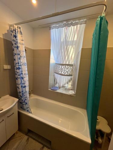a bathroom with a tub and a window and a sink at Warmiński Apartament in Biskupiec