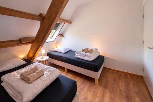 two beds in a small room with wooden beams at Ballumerhoeve Fleuri lodge in Ballum