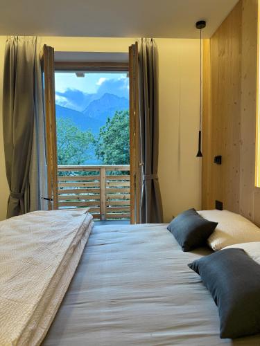 a bedroom with a large bed with a large window at Appartamento Rododendro in Andalo