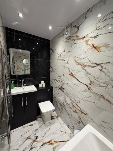 a bathroom with a white toilet and a marble wall at CityWest Apartments in Newcastle upon Tyne