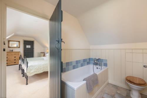 a bathroom with a bath tub and a bedroom at The Coach House at Noelles Cottages in Pickering
