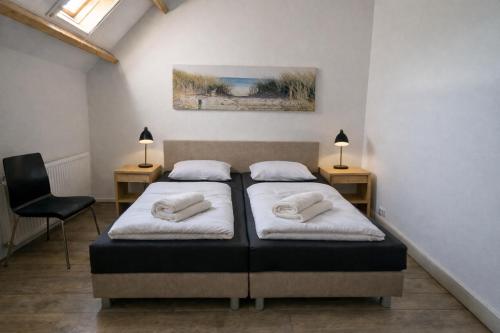 two beds in a room with two lamps and a chair at Ballumerhoeve Petit lodge in Ballum