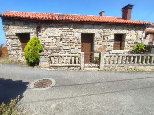 a stone house with a gate and a fence at O Iniño casita rural costera in O Grove