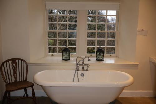 a white bath tub in a bathroom with a window at Forget Me Not Holiday Cottage in Dalmellington