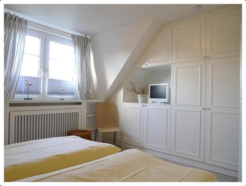 a white bedroom with two beds and a window at Haus-Kim in Tinnum
