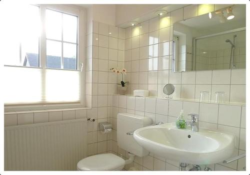 a bathroom with a sink and a toilet and a mirror at Haus-Kim in Tinnum