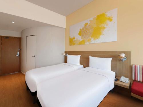 two beds in a hotel room with white sheets at ibis Pune Hinjewadi - An Accor Brand in Pune
