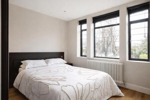 a white bedroom with a bed and two windows at Spacious King Room on the Heart of Chiswick West London in London