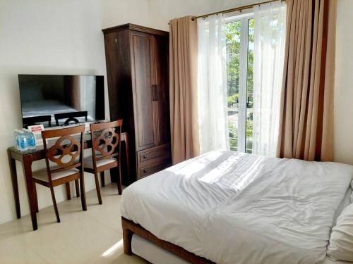 a bedroom with a bed and a desk and a window at Affordable Stylish & Cozy Walk Up Condo in Minglanilla