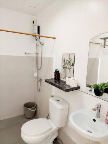 a white bathroom with a toilet and a sink at Affordable Stylish & Cozy Walk Up Condo in Minglanilla