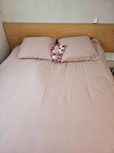a pink bed with two pillows and flowers on it at mobil-home in Souméras