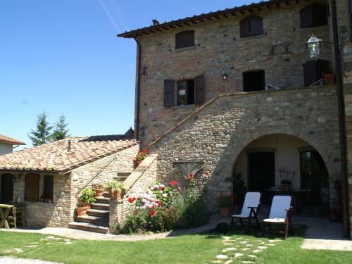 - un grand bâtiment en pierre avec 2 chaises et des fleurs dans l'établissement Modern Holiday Home in Montone with Pool, à Montone