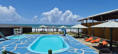 a swimming pool with a water slide and the beach at Pousada Club de Poças in Conde