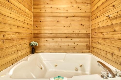 a bath tub in a bathroom with wooden walls at Amazing Grace-Cozy Cabin Retreat in the Smokies in Sevierville