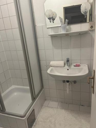 a white bathroom with a sink and a shower at Double Room Stegersbach in Stegersbach