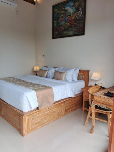 a bedroom with a large bed with a picture on the wall at Umakami Pertiwi Villas in Ubud