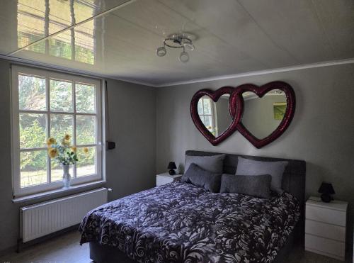 a bedroom with a bed and a mirror with hearts on the wall at Ferienhaus Herzkate in Bremervörde
