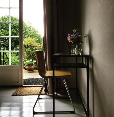 a table and a chair with a vase of flowers at Ravlunda Bränneri in Kivik