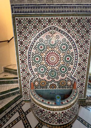 a mosaic wall with a tub in a room at Dar Jnan EL Sbil in Fez