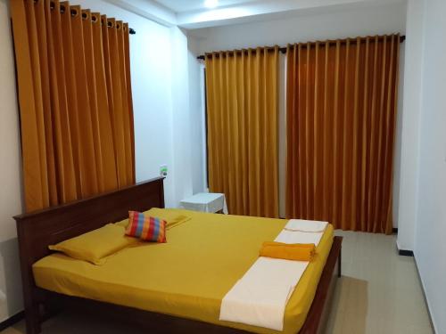 a bedroom with a yellow bed with orange curtains at Jb Villa in Bona Vista
