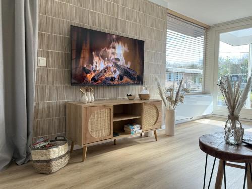 a living room with a fireplace and a tv on the wall at Wellness huisje Sonne Oase in Lanaken
