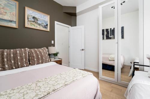 a bedroom with a white bed and a mirror at Spacious 2BR near UofT and College in Toronto