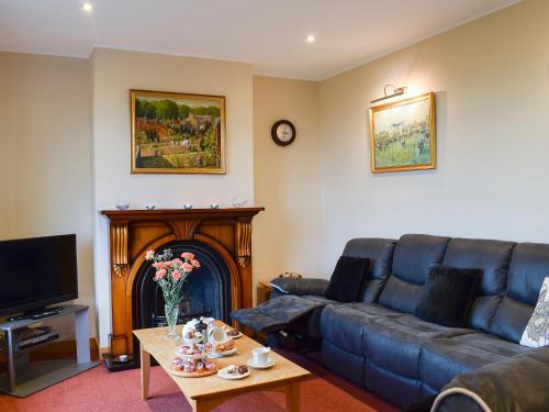a living room with a blue couch and a fireplace at Bankhead Farm Cottage in Donibristle