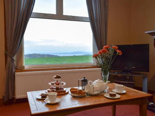a coffee table with tea and biscuits and a window at Bankhead Farm Cottage in Donibristle