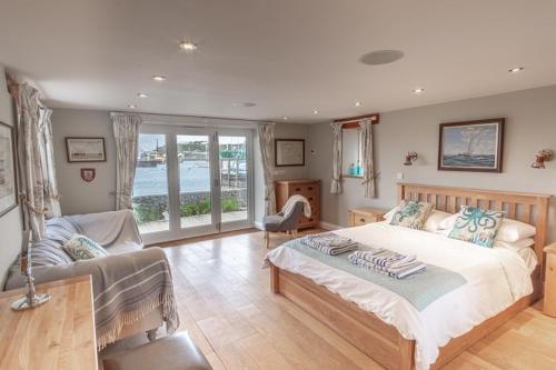 a bedroom with a large bed and a couch at Waterfront Boathouse - Drift Cottage in Plymouth