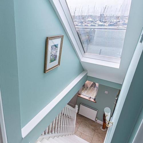 a stairway with a blue wall and a window at Waterfront Boathouse - Drift Cottage in Plymouth