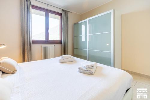 a bedroom with a white bed with towels on it at LA VISTA by Design Studio in Bellano