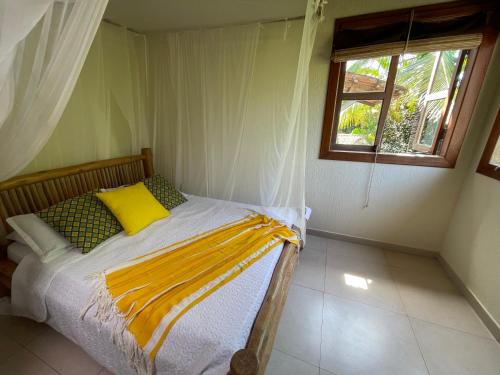 a bedroom with a bed with a yellow pillow and a window at Pousada Royale in Arraial d'Ajuda