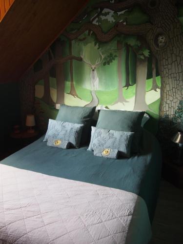 a bedroom with a bed with a tree wall at La Sorcière et le Korrigan in Paimpont