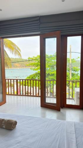 a bedroom with a view of the ocean from a balcony at Surf Villa Hiriketiya in Hiriketiya