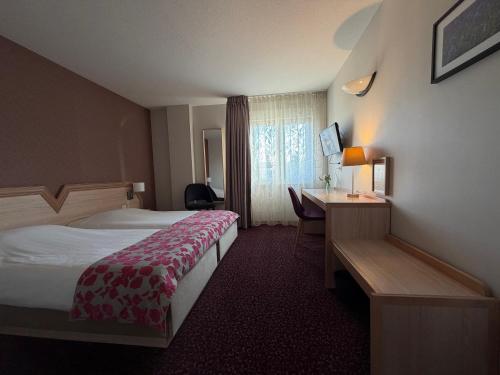 a hotel room with a bed and a desk at Au Relais de l'Ill in Sermersheim