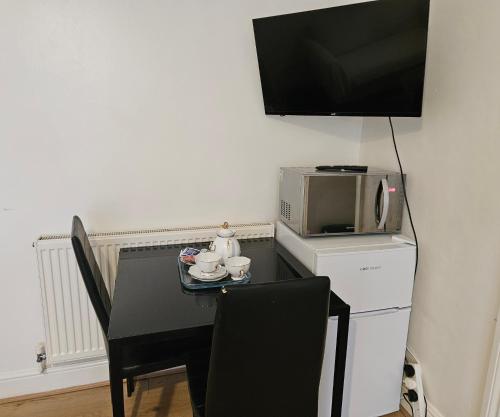 a dining room table with a microwave and a television at Lovely studio flat in Reading